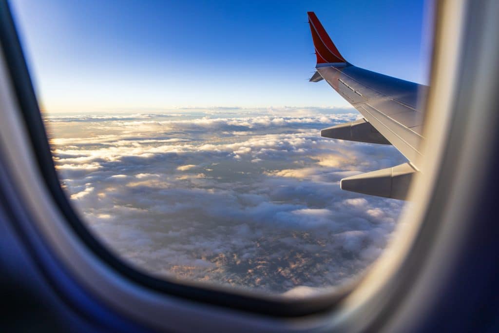Looking out window of aircraft while flying above the clouds